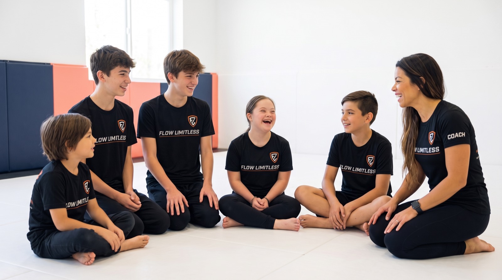 An inclusive group of kids and their coach celebrating together on the mats